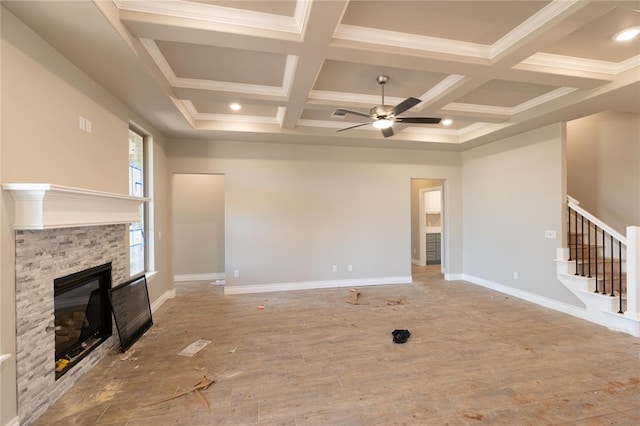 16024 Coneflower Dr, Edmond, OK 73013 - unfurnished living room featuring ceiling fan, a stone fireplace, coffered ceiling, stairway, and beam ceiling