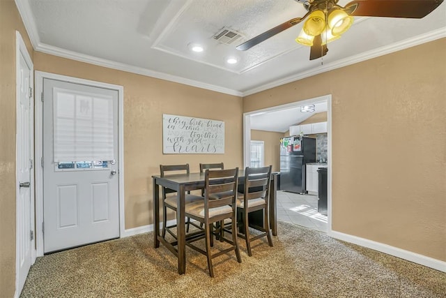 dining space with ceiling fan, light colored carpet, a textured ceiling, and ornamental molding