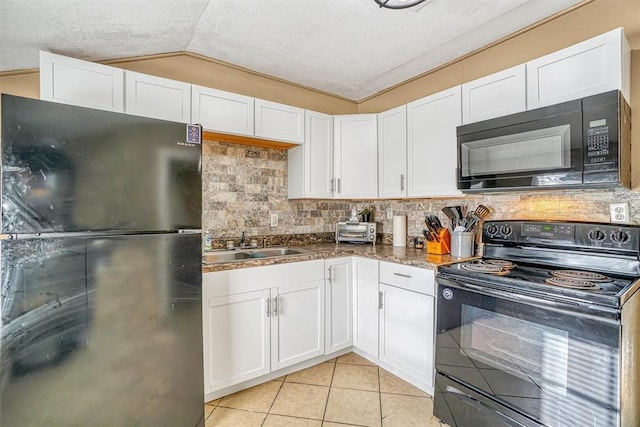 kitchen with white cabinets, vaulted ceiling, and black appliances