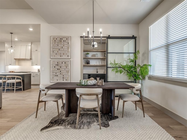 dining area featuring light wood-type flooring, a notable chandelier, and a wealth of natural light