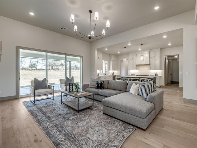 living room with sink, light hardwood / wood-style flooring, and a chandelier