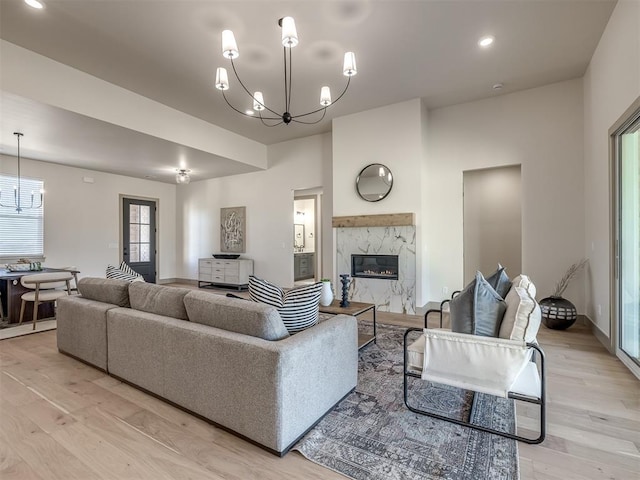 living room featuring a high end fireplace, light hardwood / wood-style floors, and a chandelier