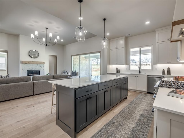 kitchen with white cabinets, a high end fireplace, pendant lighting, and a kitchen island