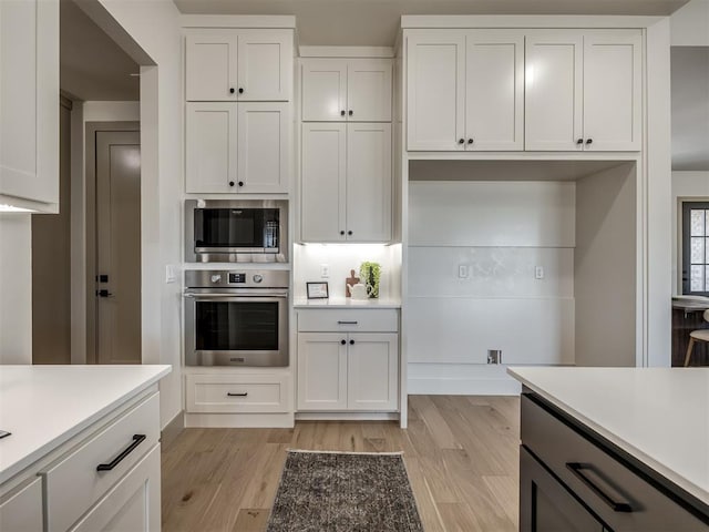 kitchen with white cabinets, light wood-type flooring, and stainless steel appliances