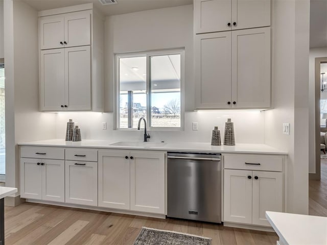 kitchen featuring light wood-type flooring, dishwasher, sink, and white cabinetry