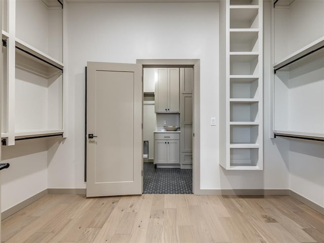 walk in closet with light hardwood / wood-style flooring