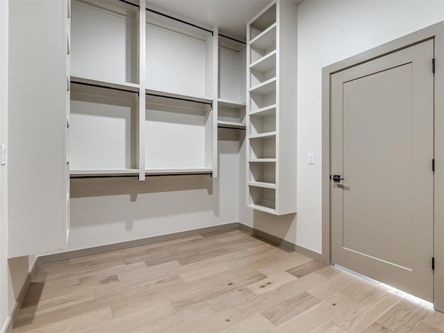 walk in closet with light hardwood / wood-style flooring