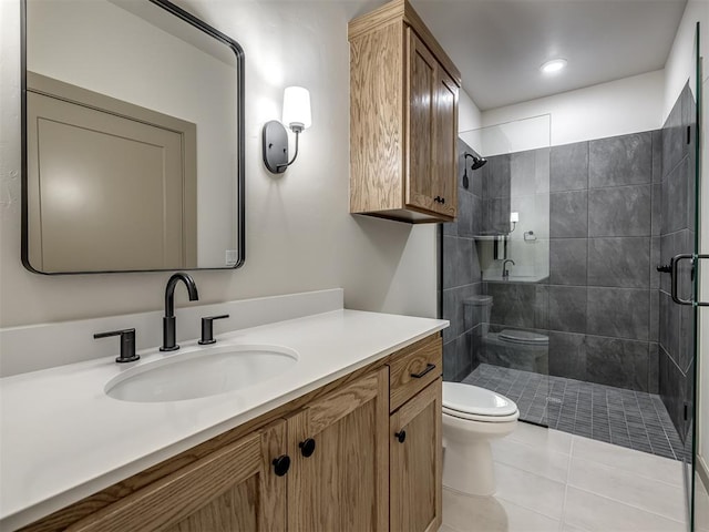 bathroom with toilet, vanity, tile patterned flooring, and a tile shower