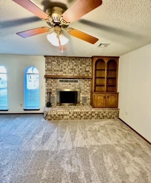 unfurnished living room with light carpet, ceiling fan, a textured ceiling, and a brick fireplace