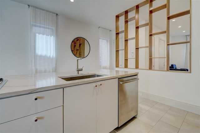 kitchen with white cabinetry, sink, light stone counters, stainless steel dishwasher, and light tile patterned floors