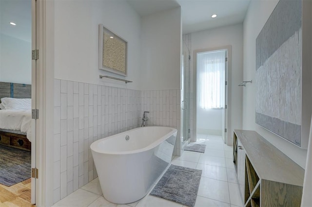 bathroom with tile patterned flooring, vanity, tile walls, and plus walk in shower