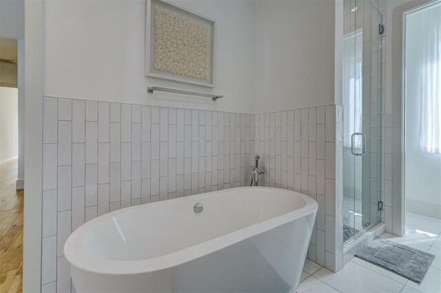 bathroom featuring tile patterned flooring, tile walls, and independent shower and bath