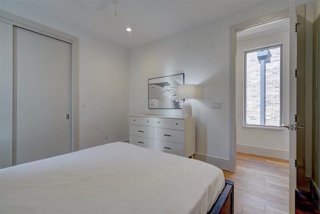 bedroom with ceiling fan, a closet, and light hardwood / wood-style flooring