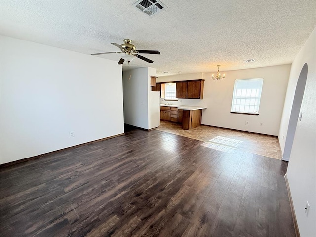 unfurnished living room featuring a textured ceiling, dark hardwood / wood-style flooring, and ceiling fan with notable chandelier