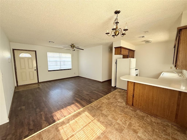 kitchen with a textured ceiling, white fridge, hanging light fixtures, and ceiling fan with notable chandelier