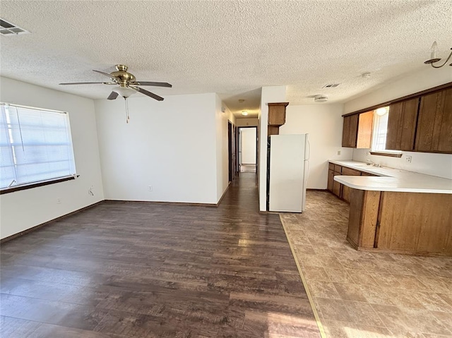 kitchen featuring a textured ceiling, white fridge, ceiling fan, and dark hardwood / wood-style floors