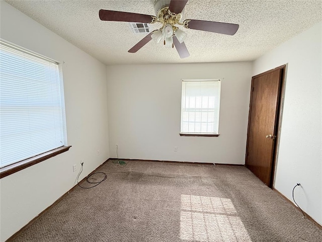 carpeted empty room featuring ceiling fan and a textured ceiling