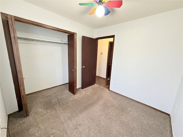 unfurnished bedroom with carpet flooring, ceiling fan, a closet, and a textured ceiling