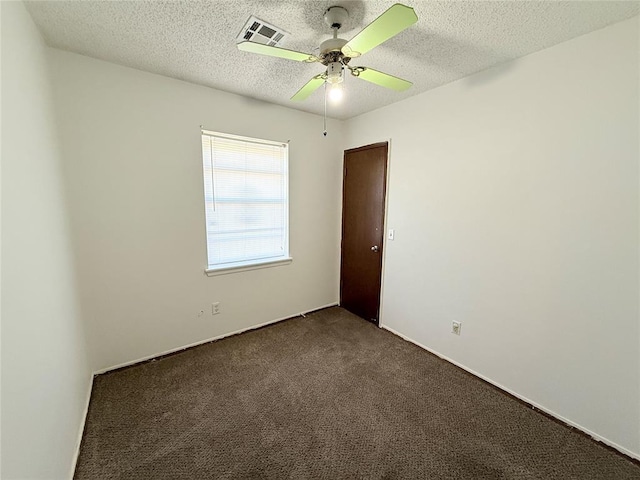 empty room with dark colored carpet, a textured ceiling, and ceiling fan