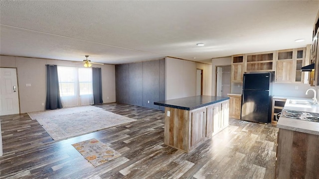 kitchen with black fridge, a kitchen island, dark wood-type flooring, and ceiling fan