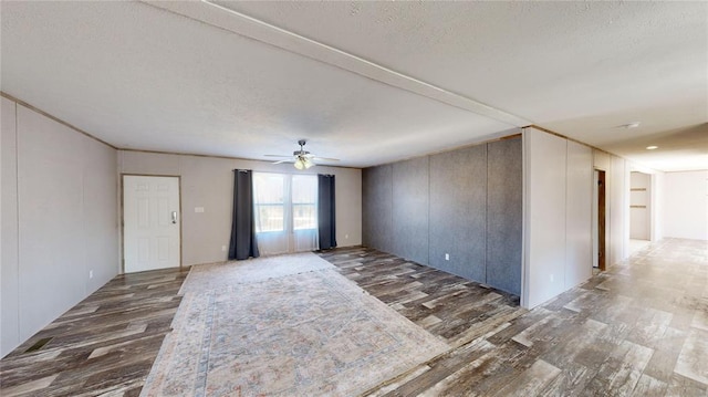 spare room with a textured ceiling, ceiling fan, and dark wood-type flooring