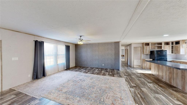 unfurnished living room featuring ceiling fan, dark hardwood / wood-style floors, and a textured ceiling