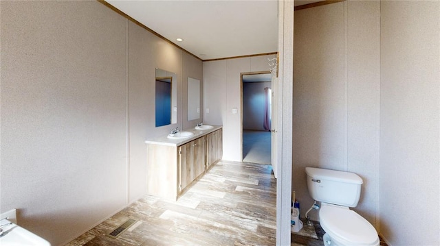 bathroom with wood-type flooring, vanity, toilet, and ornamental molding