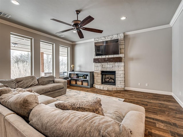 living room featuring ceiling fan, ornamental molding, a stone fireplace, and dark hardwood / wood-style flooring