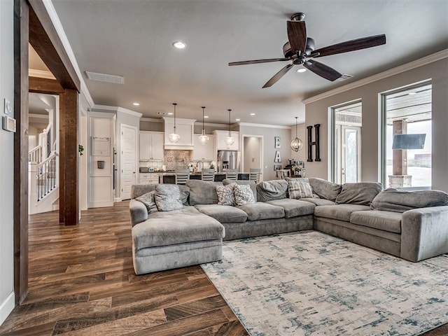 living room with dark wood-type flooring, ornamental molding, and ceiling fan