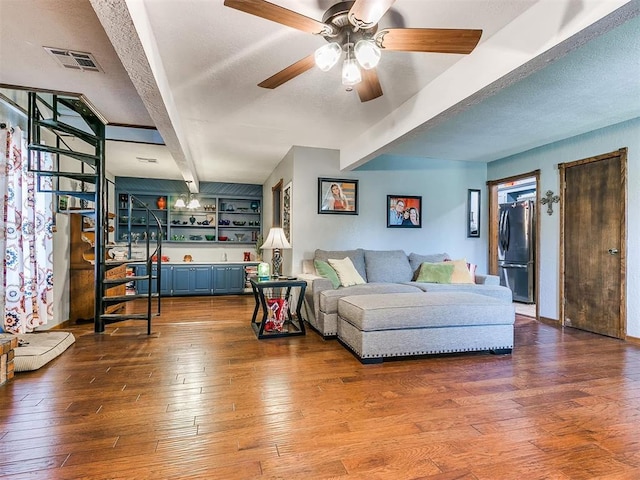 living room with ceiling fan, beam ceiling, and wood-type flooring