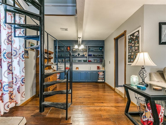 bar with wine cooler, an inviting chandelier, blue cabinets, and hardwood / wood-style flooring