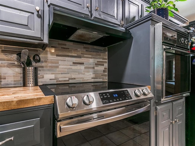 kitchen featuring decorative backsplash, electric range, tile patterned flooring, butcher block countertops, and oven