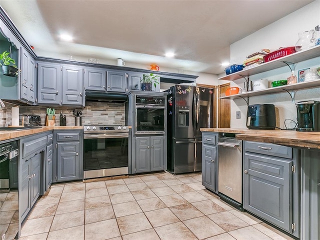 kitchen featuring wooden counters, light tile patterned floors, backsplash, and black appliances