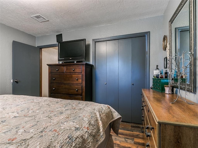 bedroom featuring a textured ceiling, a closet, and dark wood-type flooring