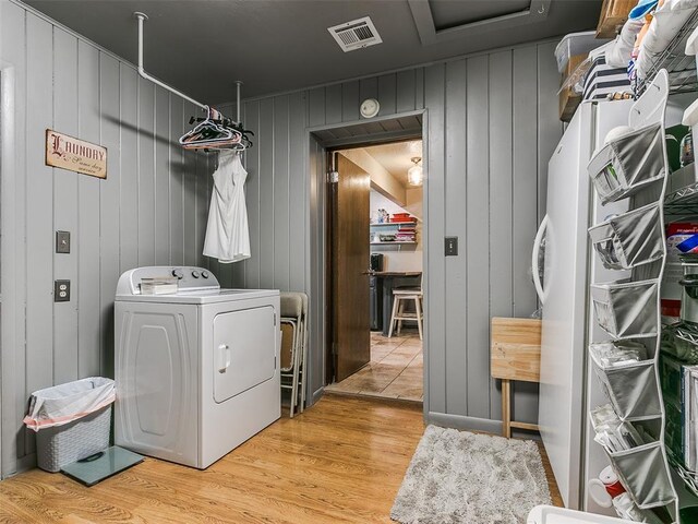 laundry room featuring washer / dryer, wood walls, and hardwood / wood-style floors