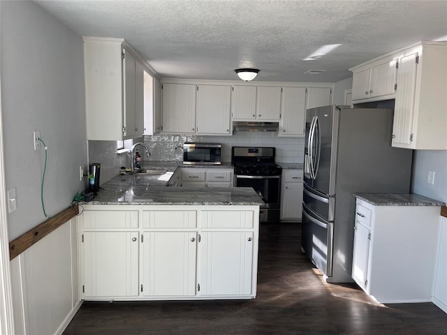 kitchen with sink, stainless steel appliances, dark hardwood / wood-style flooring, kitchen peninsula, and white cabinets