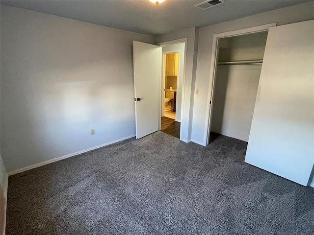 unfurnished bedroom with dark colored carpet and a closet