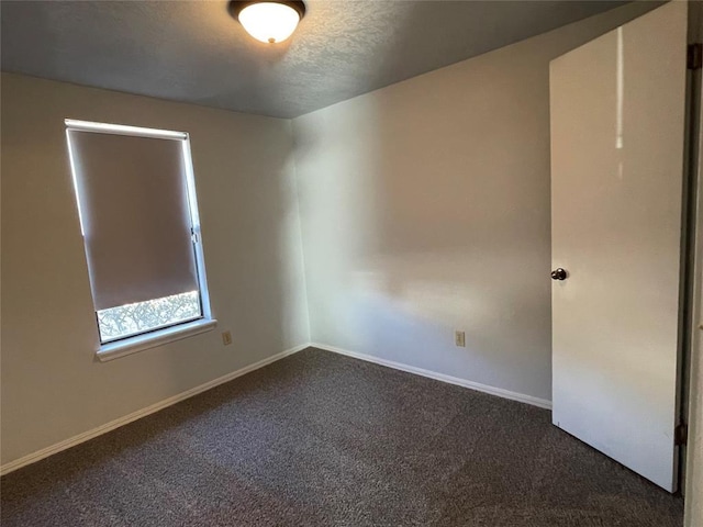 unfurnished room with dark carpet and a textured ceiling