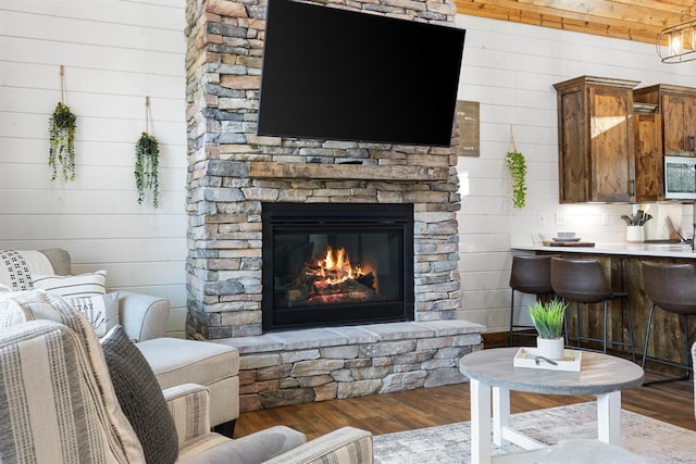 living room featuring hardwood / wood-style flooring, wood walls, and a fireplace