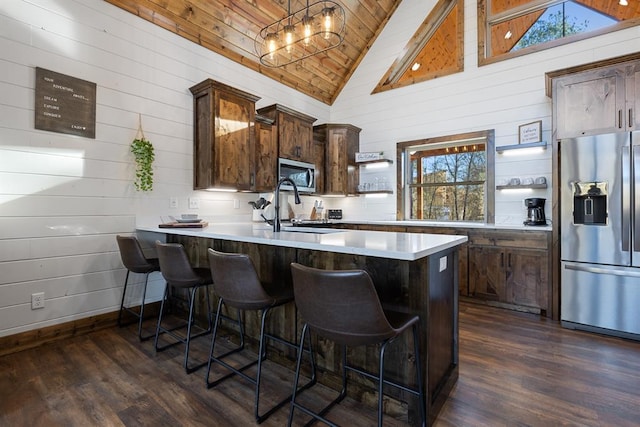 kitchen with kitchen peninsula, a breakfast bar, stainless steel appliances, and dark hardwood / wood-style flooring