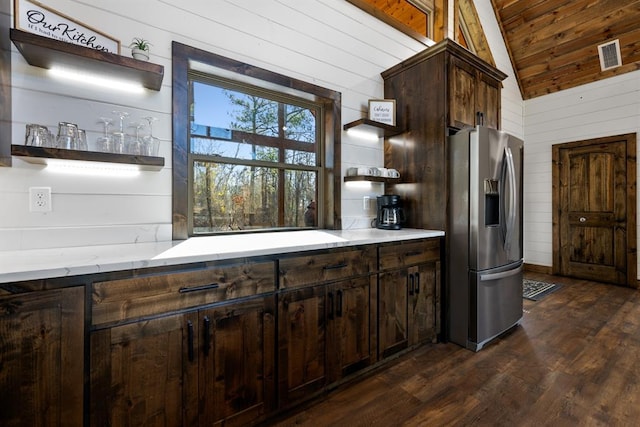 kitchen featuring vaulted ceiling, wooden walls, dark hardwood / wood-style flooring, and stainless steel refrigerator with ice dispenser