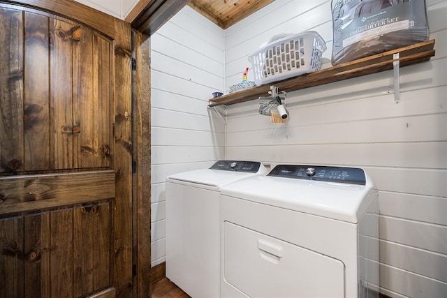 washroom with washer and clothes dryer and wood walls