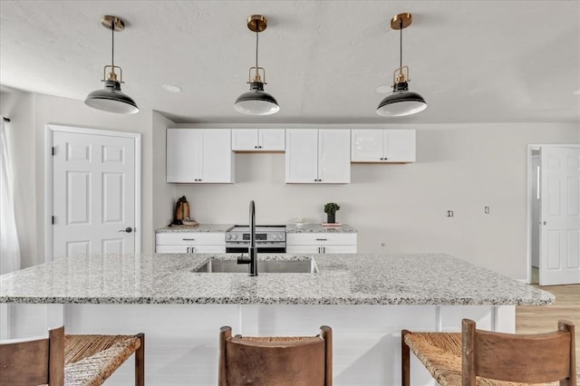 kitchen featuring white cabinets, pendant lighting, and light stone countertops