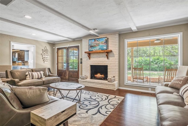 living room featuring a fireplace, beam ceiling, dark hardwood / wood-style flooring, and a textured ceiling