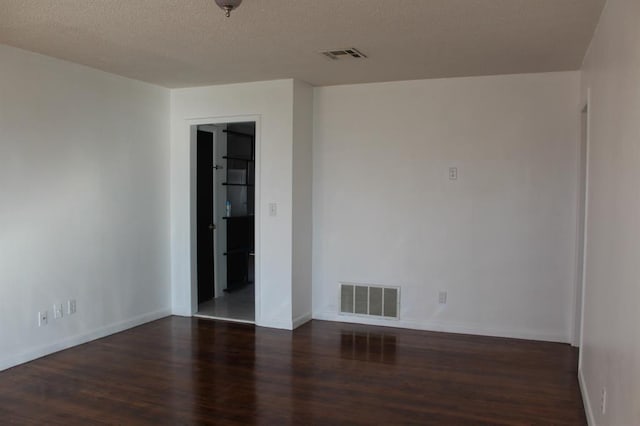 empty room featuring a textured ceiling and dark hardwood / wood-style floors