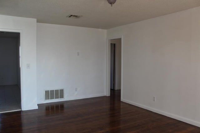 empty room featuring a textured ceiling and dark wood-type flooring