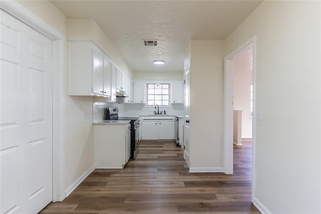 kitchen with sink, dark hardwood / wood-style floors, stainless steel range with electric cooktop, decorative backsplash, and white cabinets