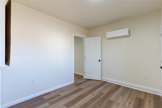 unfurnished room with an AC wall unit and light wood-type flooring