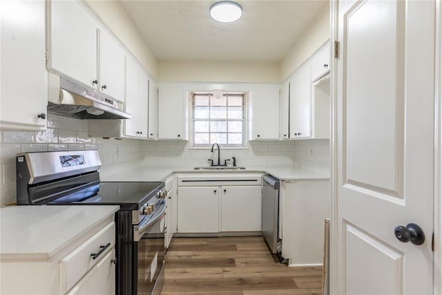 2916 SW 61st St, Oklahoma City, OK 73159 - kitchen with under cabinet range hood, white cabinets, a sink, light wood finished floors, and appliances with stainless steel finishes