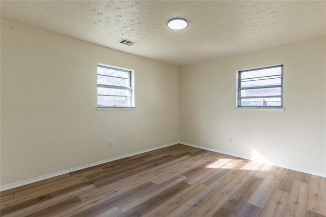 2916 SW 61st St, Oklahoma City, OK 73159 - empty room featuring baseboards, plenty of natural light, wood finished floors, and visible vents